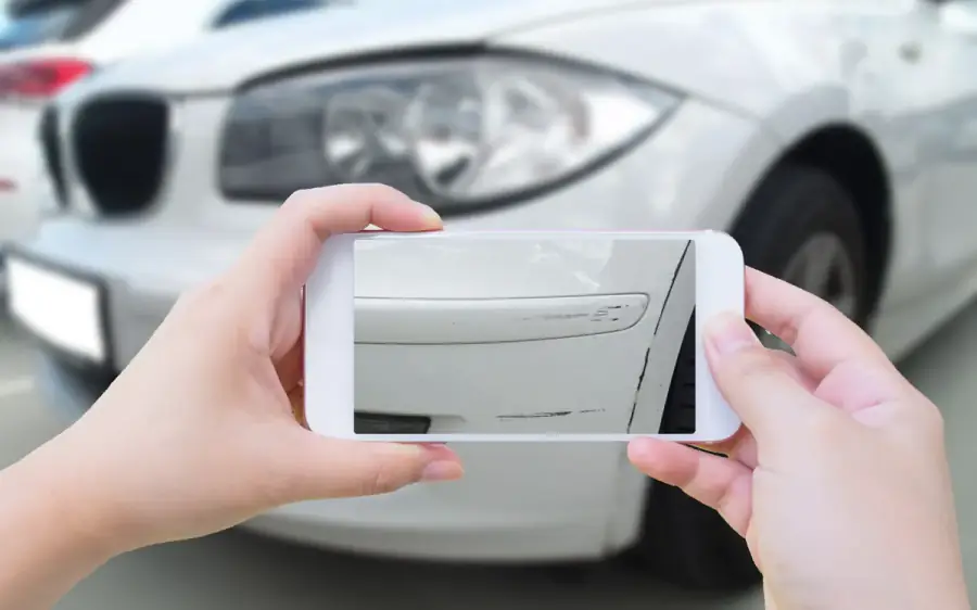 Schaden am Fahrzeug wird mit dem Smartphone fotografiert